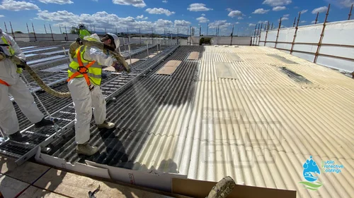 Workers spraying waterproofing coating on commercial roof