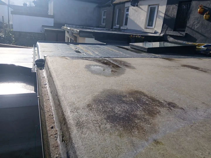 Ponding water on a flat roof surface showing signs of a roof leak