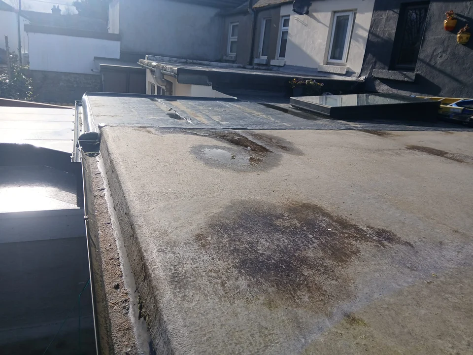 Ponding water on a flat roof surface showing signs of a roof leak