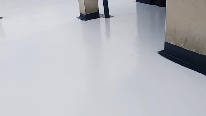 Professional roofer applying liquid waterproofing to repair a leaking flat roof