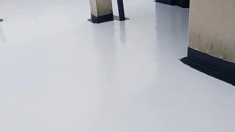 Professional roofer applying liquid waterproofing to repair a leaking flat roof