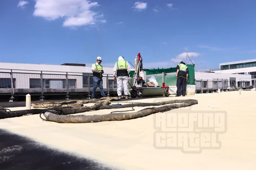 Team applying polyurea waterproofing system on large commercial roof